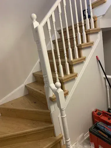 Curved wood staircase with white balusters and handrail